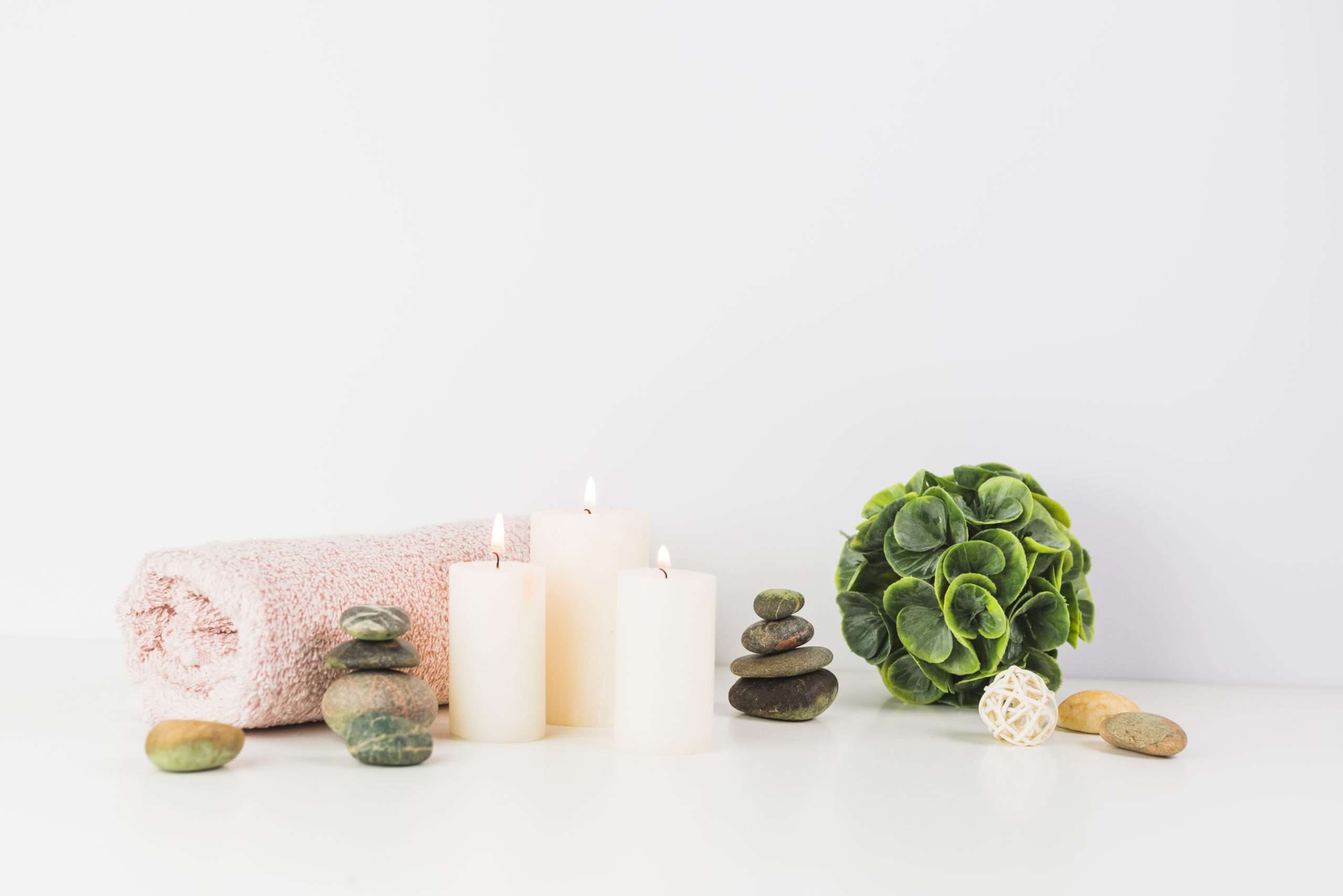 Image décoré avec les éléments du massage . Il y a une serviette avec des bougie, des pierre de massage